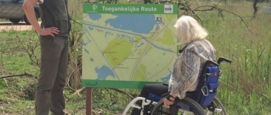Persoon in rolstoel kijkende naar plattegrond van toegankelijke route